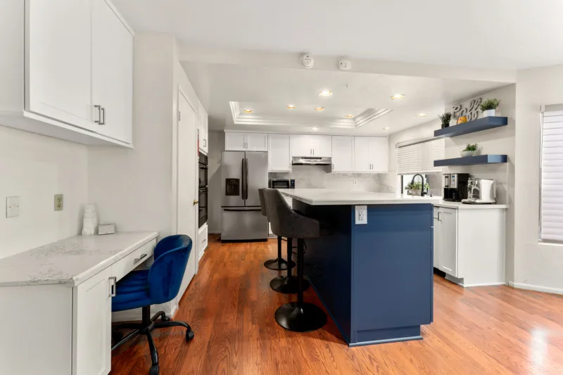 After view of white kitchen with blue island