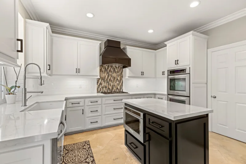After view of white kitchen with dark island
