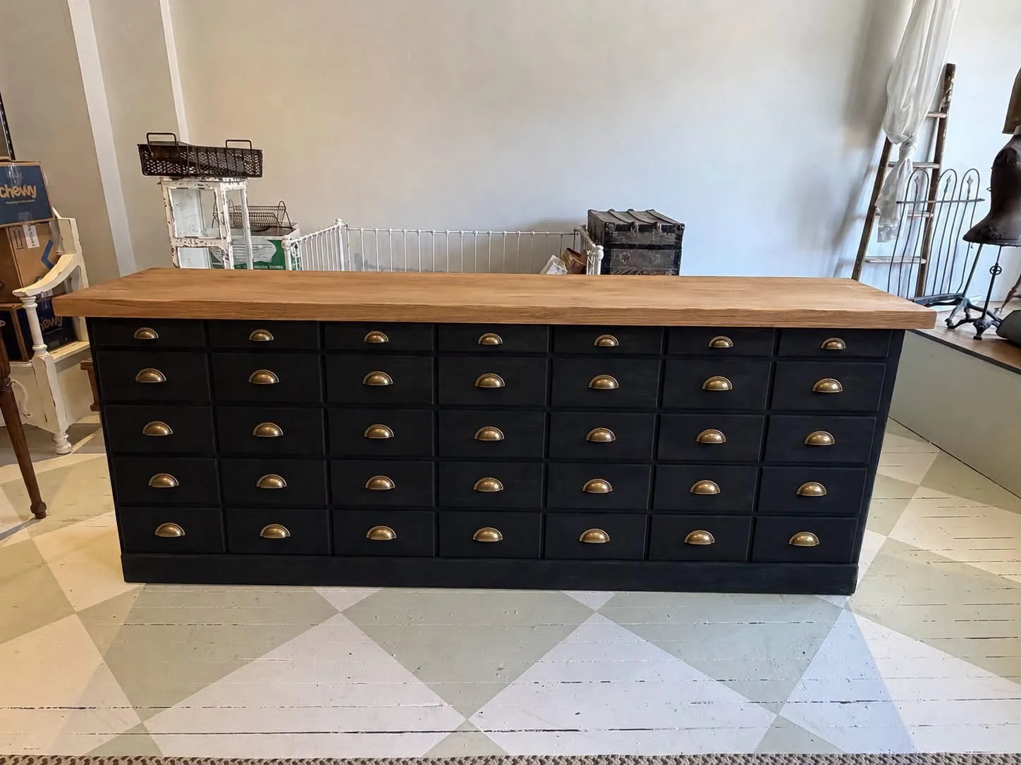 Dark cabinetry with natural wood top and brass hardware